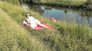 Wild beach. Sexy MILF Platinum naked sunbathing on river bank, random fisherman guy watches. Naked in public. Nude beach